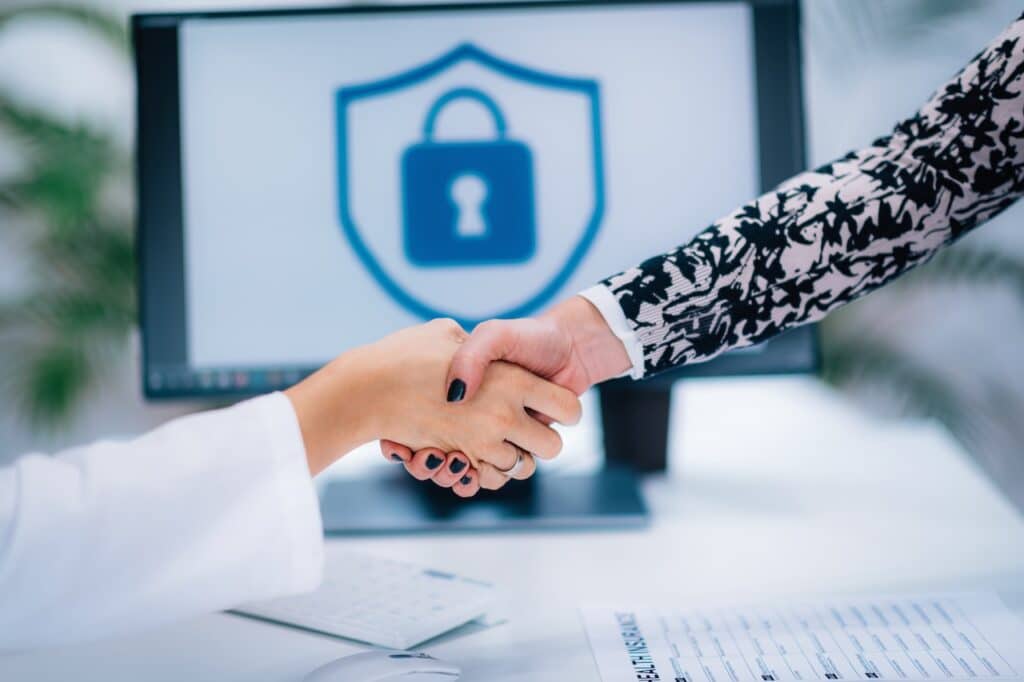 People shaking hands in front of a computer